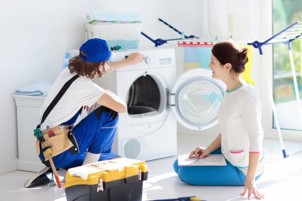 a technician repairing a washer while woman is watching - appliance repair service Trenton